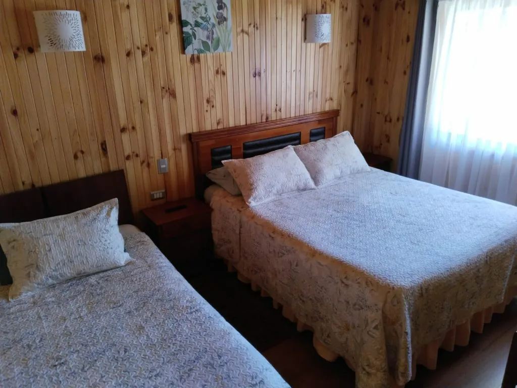 Living comedor de cabaña con estufa a leña, sillones y acceso al baño